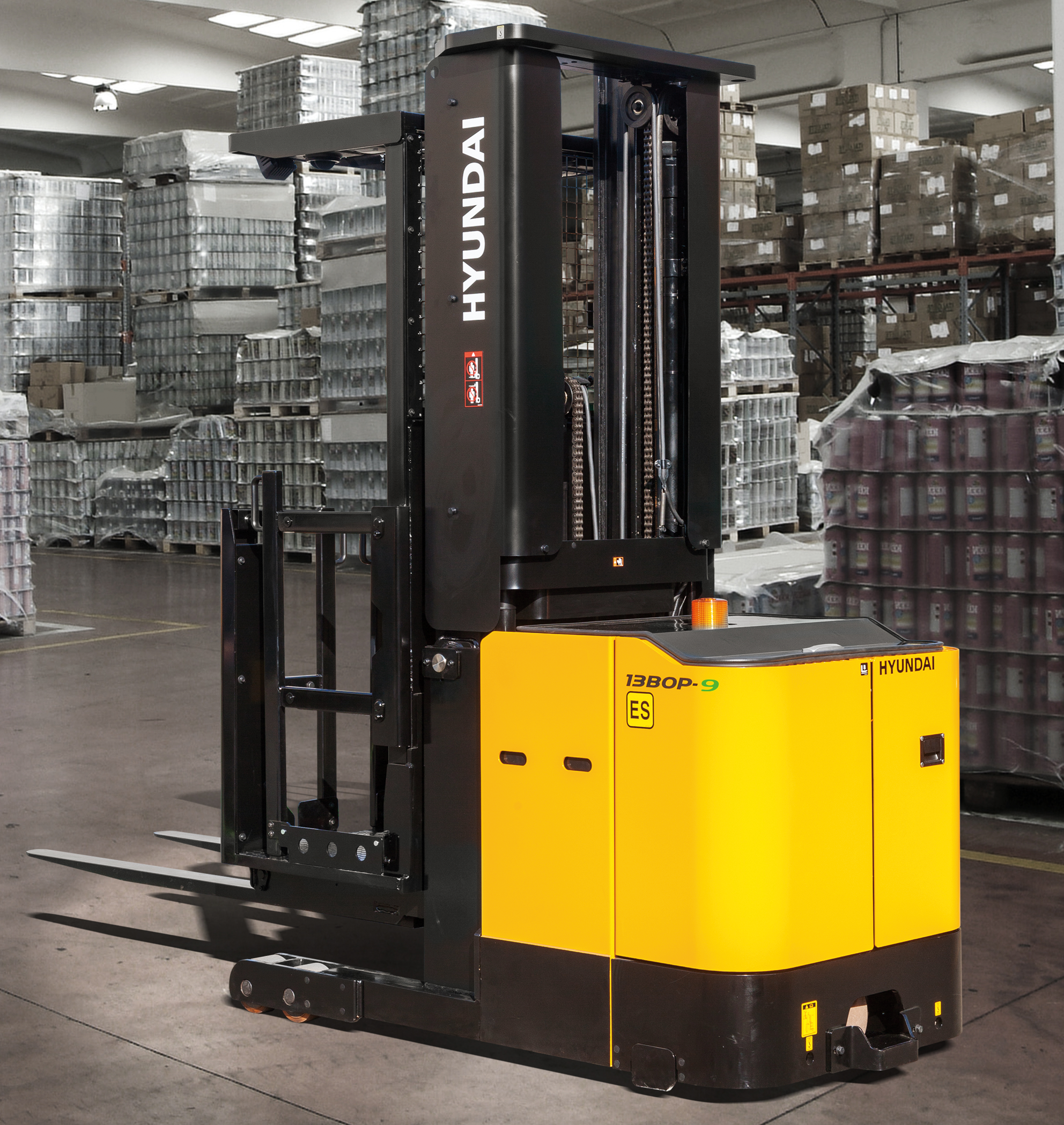 Yellow and black Hyundai 1380P-9 reach forklift on a gray concrete floor, surrounded by stacks of metal containers and boxes, with the forklift's control panel and branding visible.